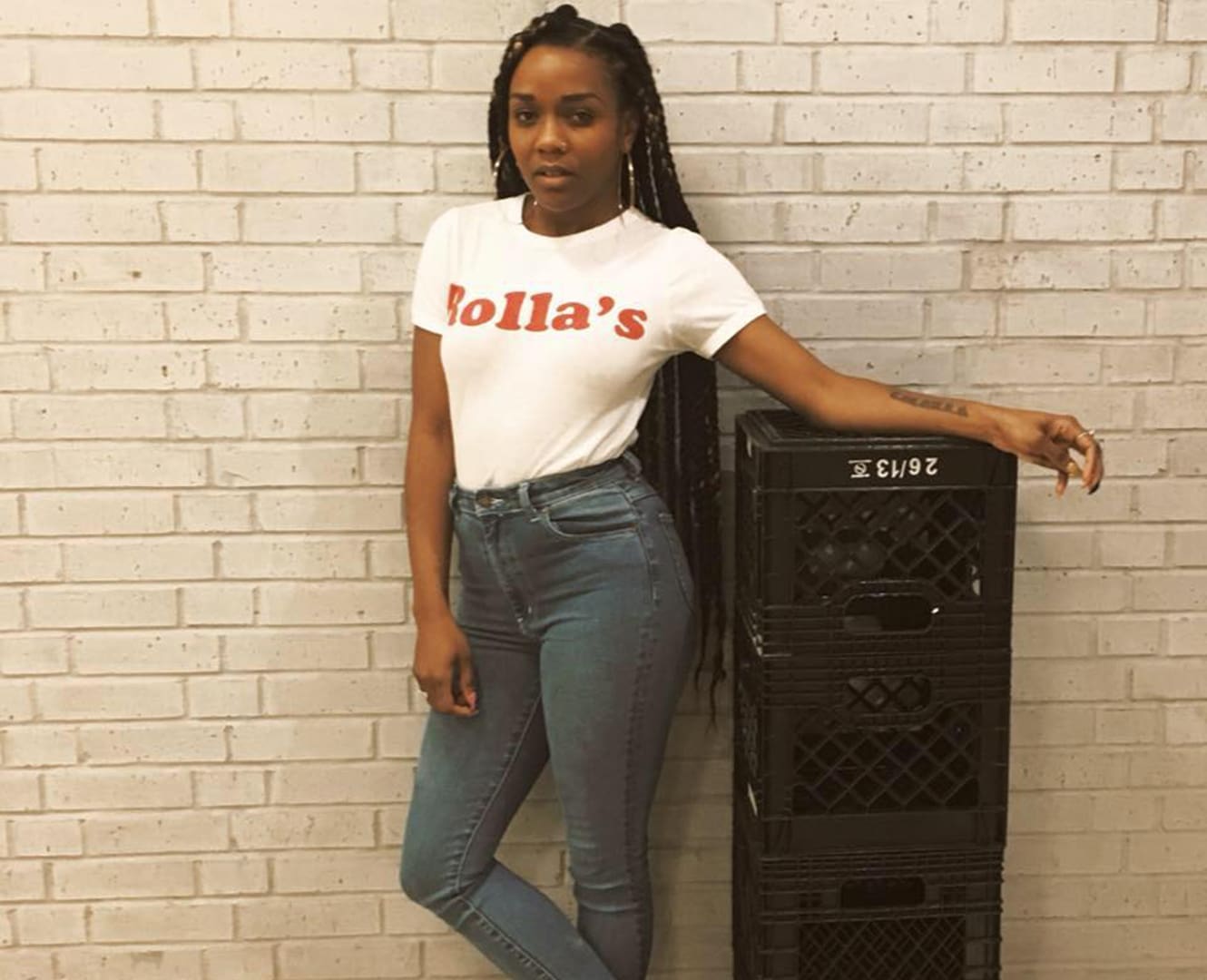 woman poses wearing red and white t-shirt in front of brick wall