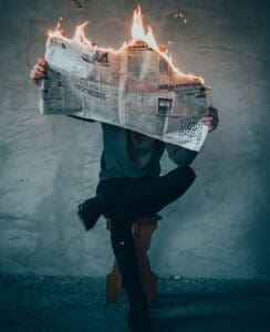 man holding newspaper burning up in flames
