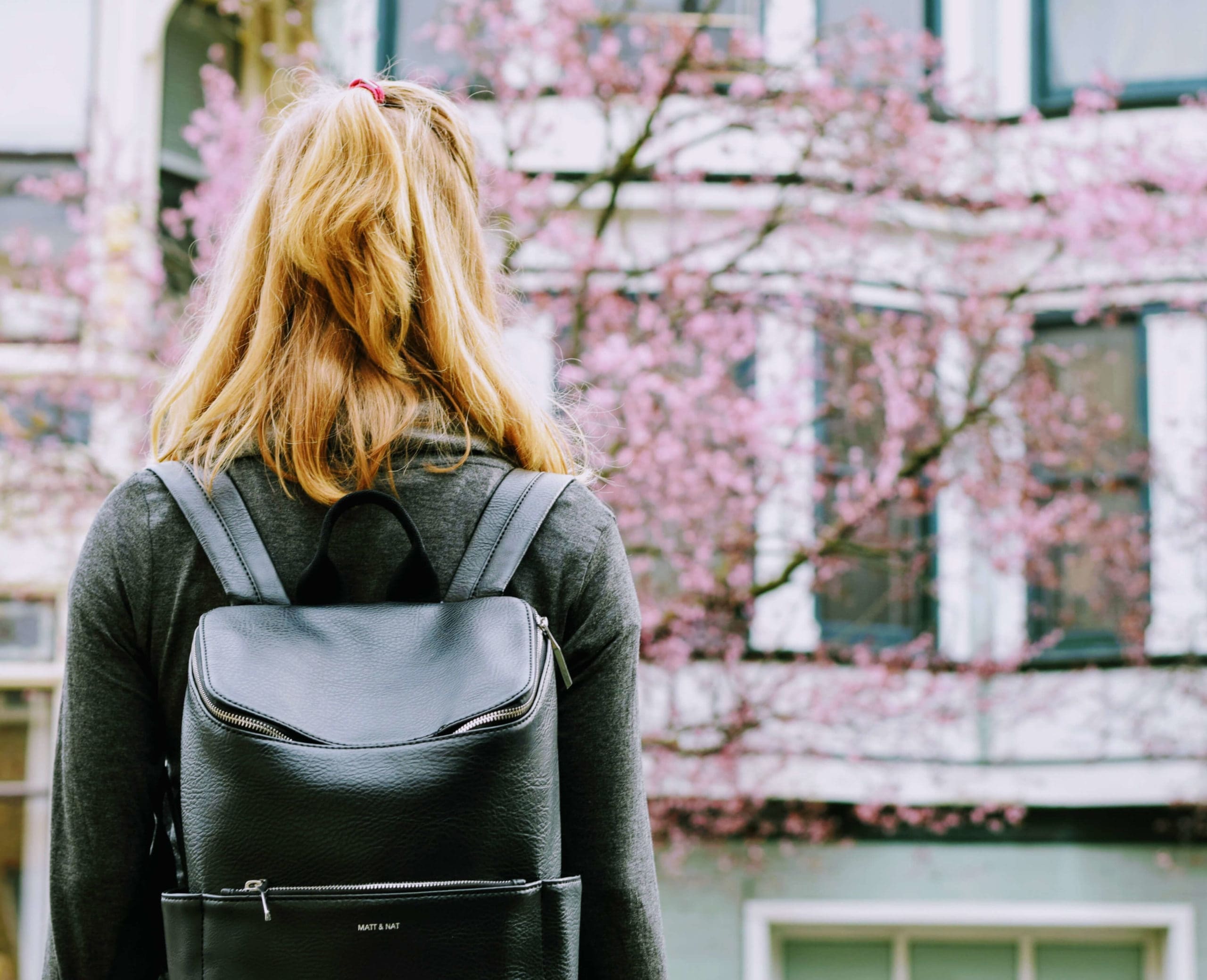 Student wearing backpack walking into school