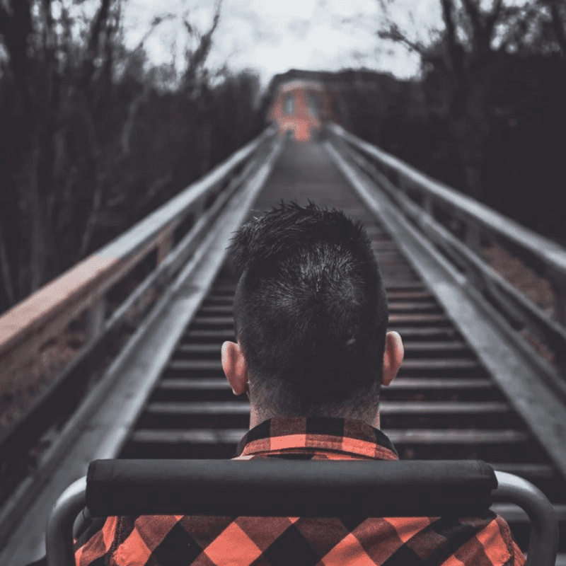 brad bartko cover man in wheelchair wearing plaid shirt overlooks a railroad track