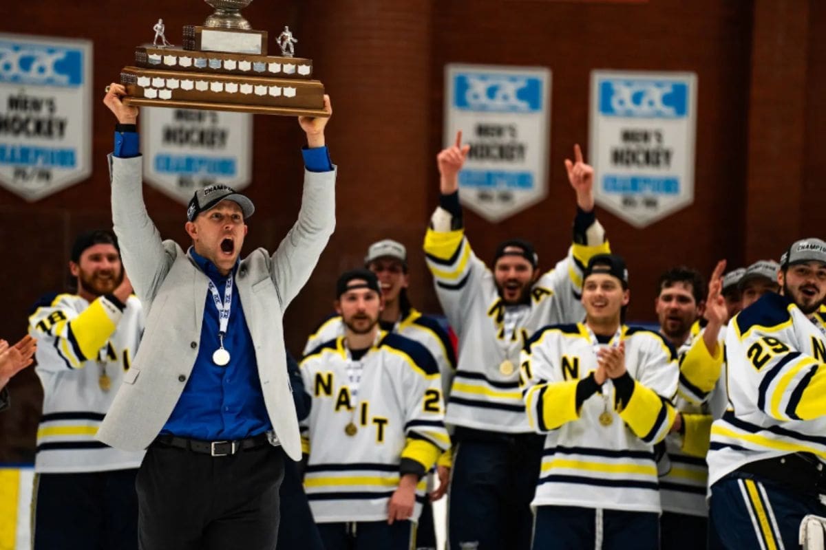 Scott Celebrates Scott Fellnermayr holds up trophy alongside cheering team as they win provincials game.