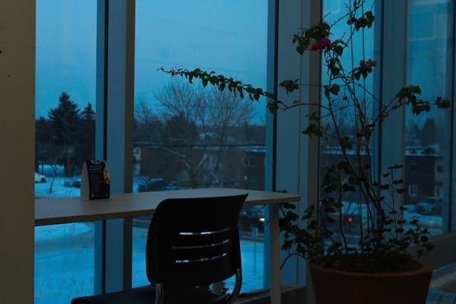 A chair in front of a bar table against a window. The lighting is dark, like it's a cold winter morning.