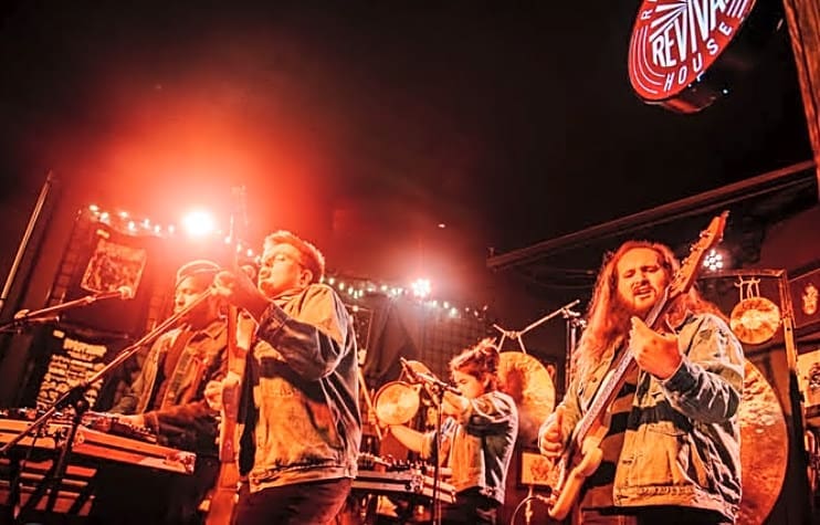 Photogrpah of guest band playing at the River City Revival House, with red lighting behind them
